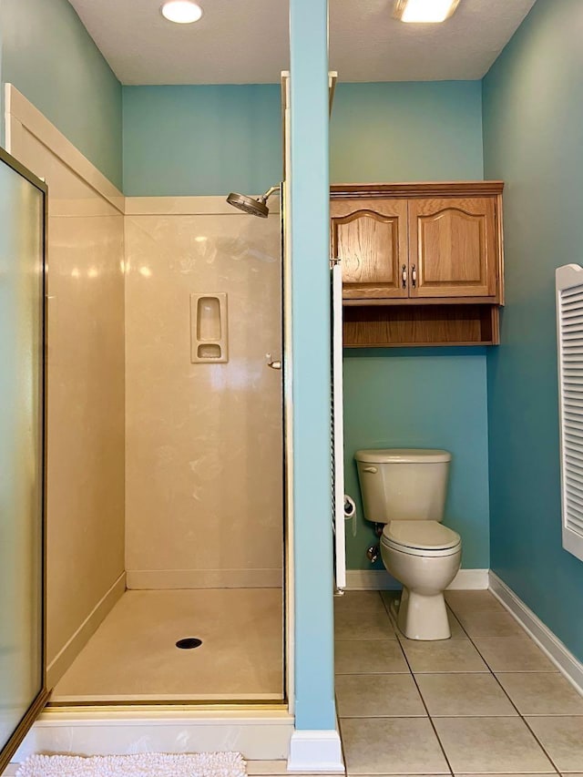 bathroom featuring toilet, tile patterned floors, and a shower with shower door