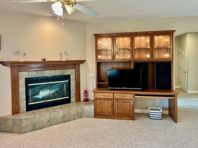 carpeted living room featuring a tile fireplace and ceiling fan