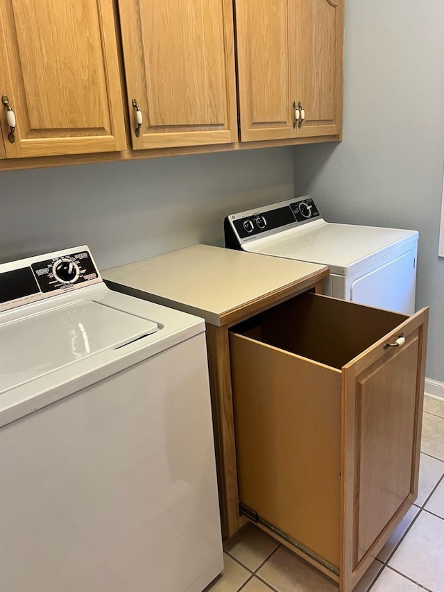 laundry room with cabinets, light tile patterned floors, and washing machine and clothes dryer