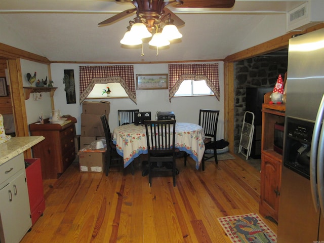 bedroom featuring stainless steel refrigerator with ice dispenser, vaulted ceiling, and light hardwood / wood-style floors