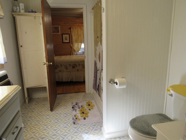 bathroom featuring vanity, wooden walls, and toilet