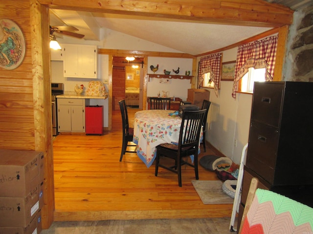 dining room with ceiling fan, light wood-type flooring, and vaulted ceiling with beams