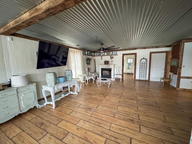 living room featuring wood-type flooring, beamed ceiling, and ceiling fan