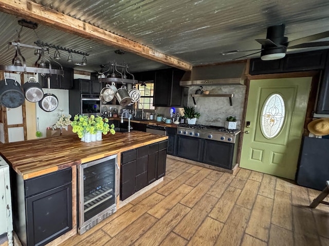 kitchen featuring appliances with stainless steel finishes, butcher block countertops, beverage cooler, light hardwood / wood-style floors, and wall chimney exhaust hood