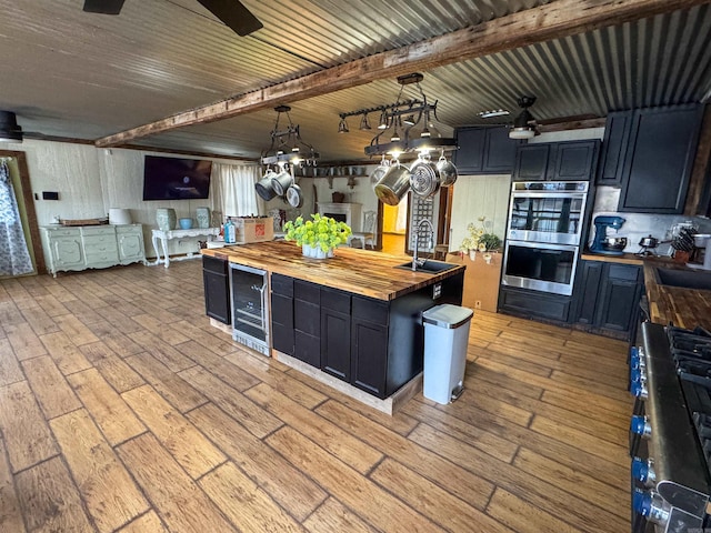 kitchen featuring double oven, decorative light fixtures, sink, wooden counters, and light hardwood / wood-style flooring