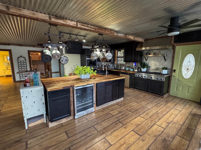 kitchen with pendant lighting, butcher block countertops, hardwood / wood-style floors, stainless steel appliances, and beverage cooler