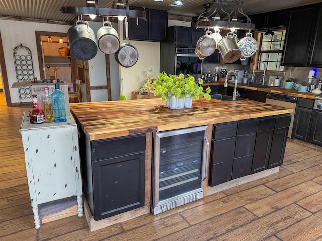 kitchen featuring sink, hanging light fixtures, wine cooler, light hardwood / wood-style floors, and wood counters