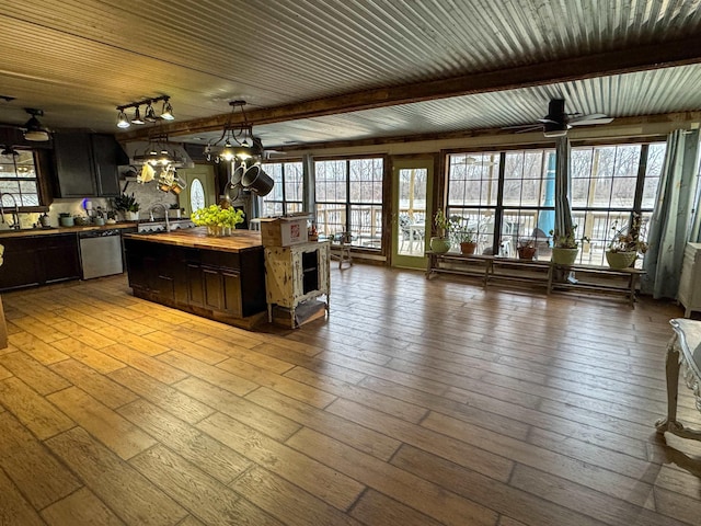 kitchen featuring stainless steel dishwasher, wooden counters, hanging light fixtures, and light hardwood / wood-style flooring