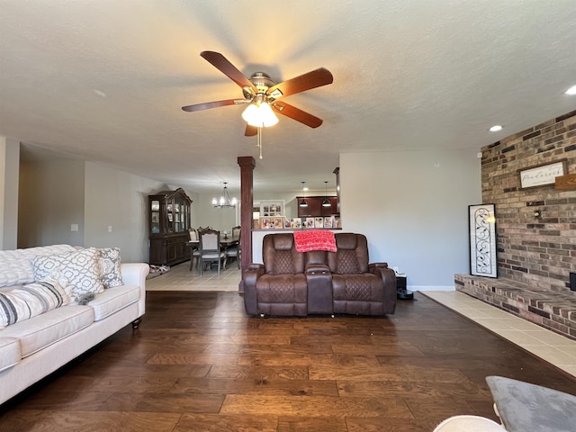 living room with dark hardwood / wood-style floors, ceiling fan with notable chandelier, and a textured ceiling