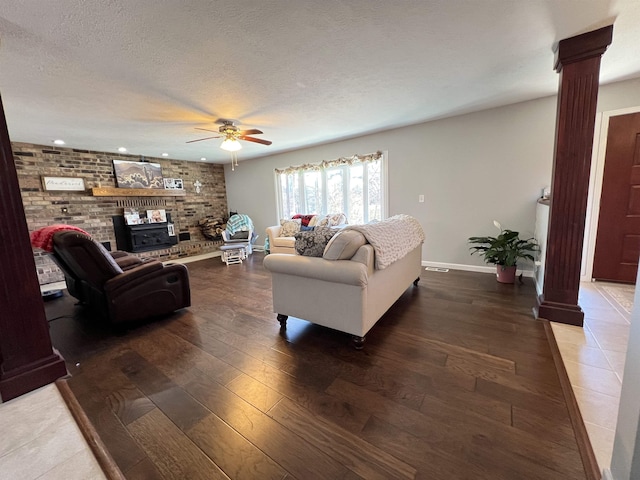 living room featuring ornate columns, ceiling fan, dark hardwood / wood-style floors, and a textured ceiling