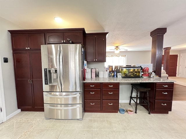 kitchen featuring light stone counters, stainless steel fridge with ice dispenser, a textured ceiling, ceiling fan, and decorative columns