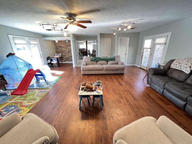 living room with dark hardwood / wood-style flooring, plenty of natural light, rail lighting, and a textured ceiling