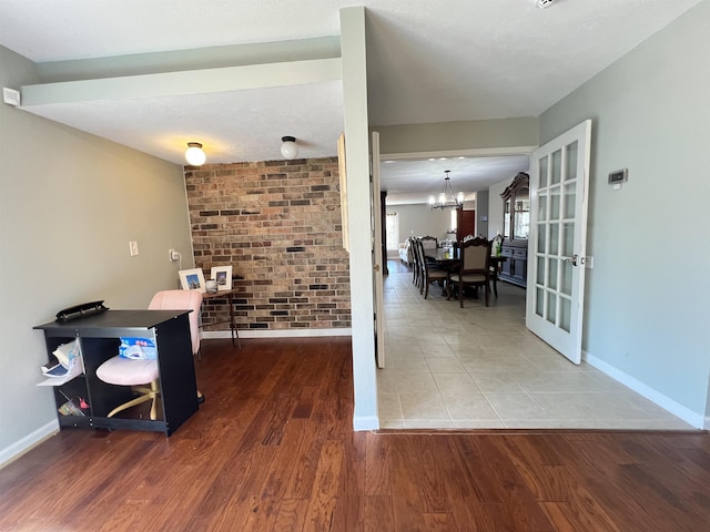 office with wood-type flooring, brick wall, a notable chandelier, and french doors