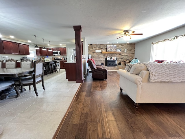 living room with ceiling fan, light hardwood / wood-style floors, a textured ceiling, and a wealth of natural light