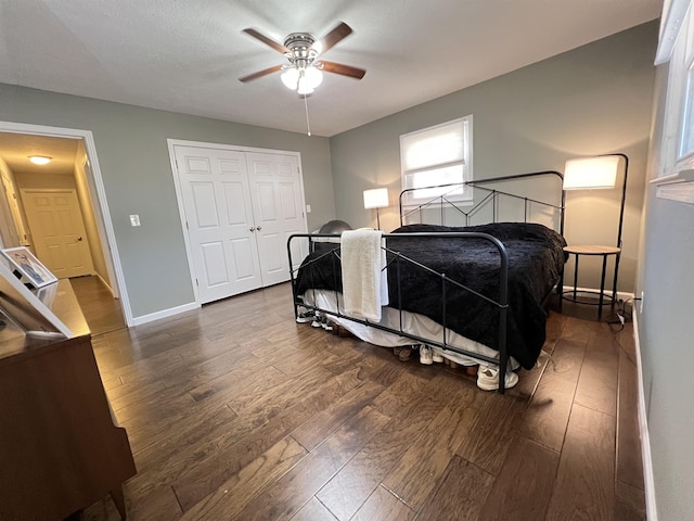 bedroom with dark wood-type flooring, ceiling fan, and a closet