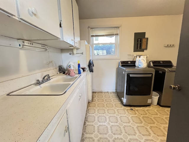 laundry room with cabinets, electric panel, sink, and washing machine and dryer