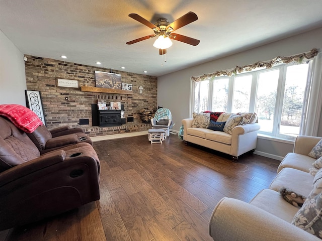 living room with hardwood / wood-style floors, brick wall, ceiling fan, and a wood stove