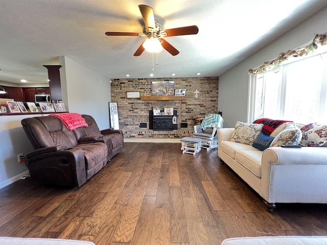 living room with ceiling fan, dark hardwood / wood-style floors, a textured ceiling, and a wood stove