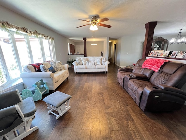 living room featuring decorative columns, plenty of natural light, ceiling fan with notable chandelier, and dark hardwood / wood-style flooring