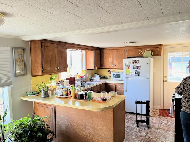 kitchen featuring white appliances, plenty of natural light, and kitchen peninsula