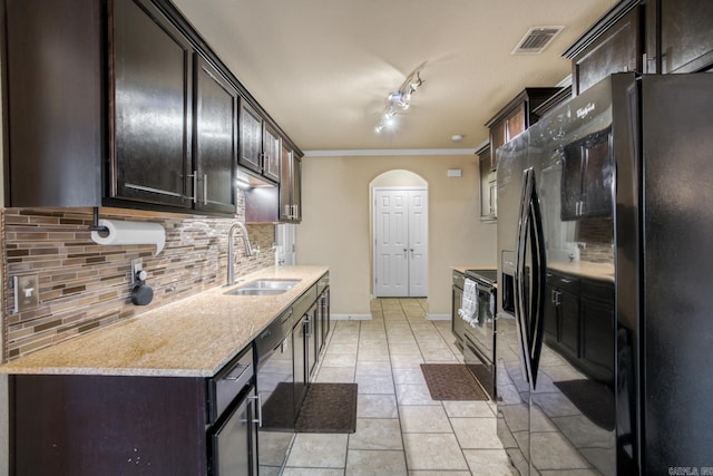 kitchen with sink, light stone counters, dark brown cabinets, decorative backsplash, and black appliances