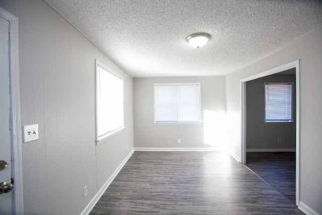 empty room with dark hardwood / wood-style flooring and a textured ceiling