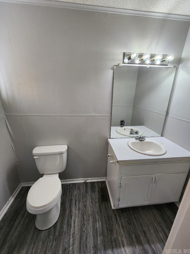 half bathroom with vanity, toilet, and wood finished floors