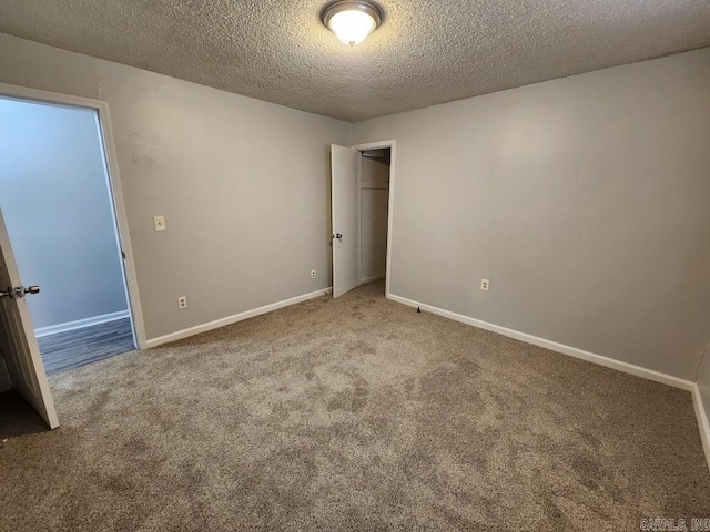 carpeted spare room featuring a textured ceiling and baseboards