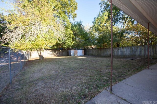 view of yard featuring a storage shed, an outdoor structure, and a fenced backyard