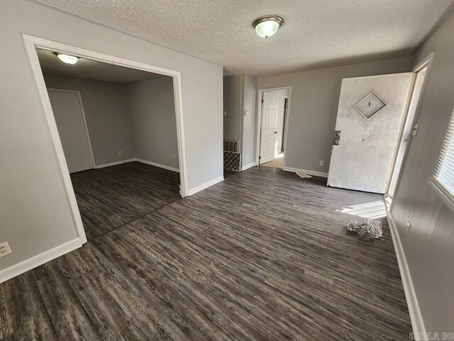 empty room featuring dark wood-style flooring, a textured ceiling, and baseboards