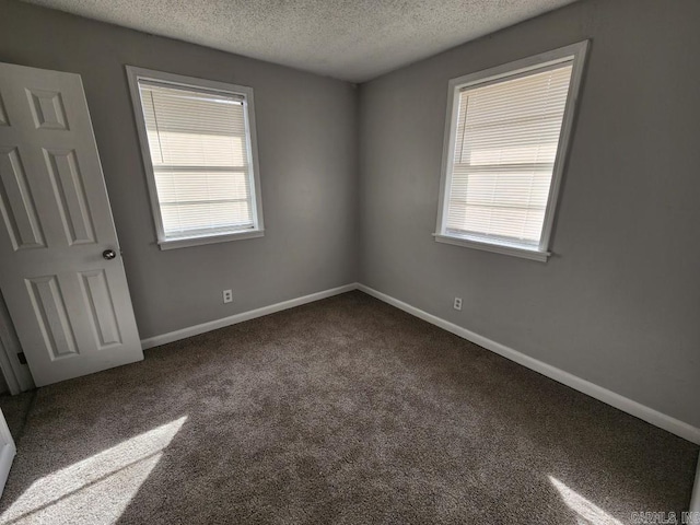 carpeted empty room featuring a textured ceiling and baseboards