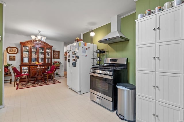 kitchen with a notable chandelier, white refrigerator with ice dispenser, green cabinetry, stainless steel range with gas cooktop, and wall chimney exhaust hood