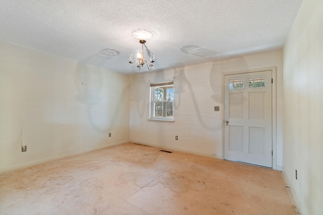 empty room with an inviting chandelier and a textured ceiling