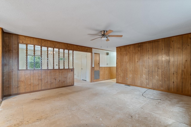 unfurnished room featuring ceiling fan and wooden walls