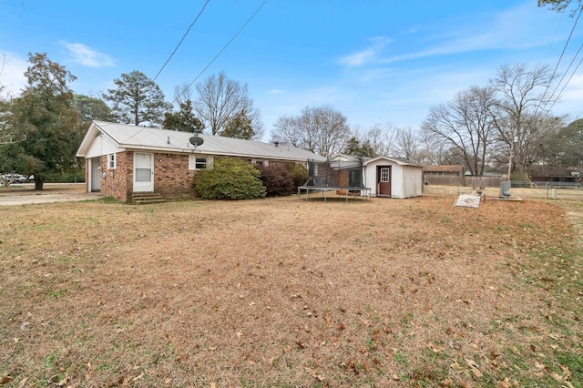 view of front of property featuring a front lawn, a trampoline, and a storage unit