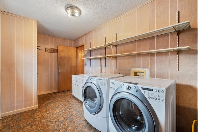 laundry room featuring cabinets, independent washer and dryer, wooden walls, and a textured ceiling