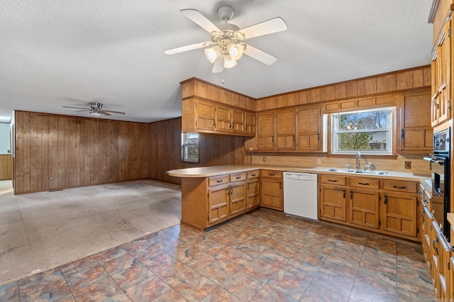 kitchen with white dishwasher, kitchen peninsula, sink, and wood walls