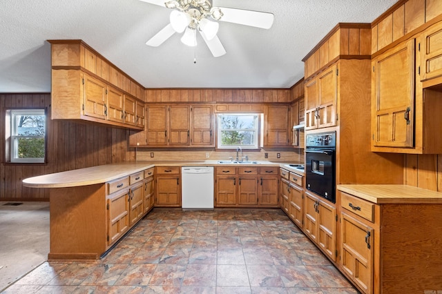 kitchen featuring plenty of natural light, white dishwasher, oven, and wood walls