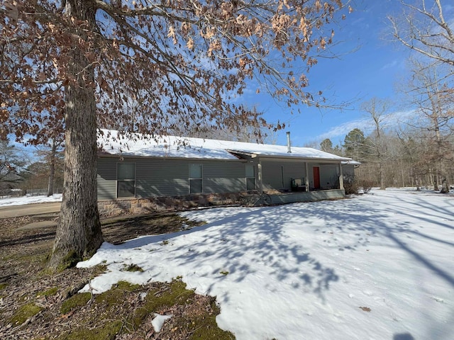 snow covered back of property with a porch