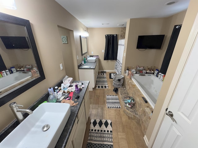 bathroom with vanity, wood-type flooring, and tiled tub