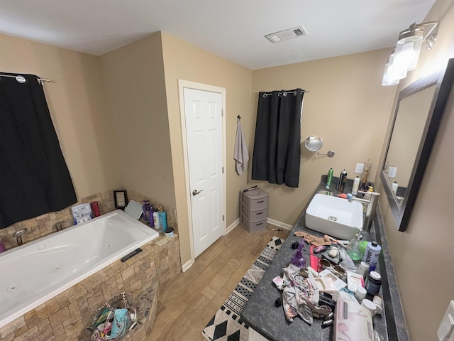 bathroom featuring tiled tub, vanity, and hardwood / wood-style floors