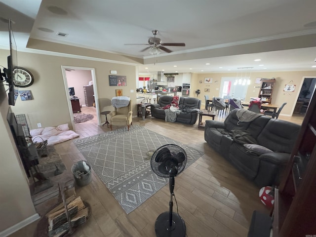 living room with hardwood / wood-style flooring, ornamental molding, and ceiling fan