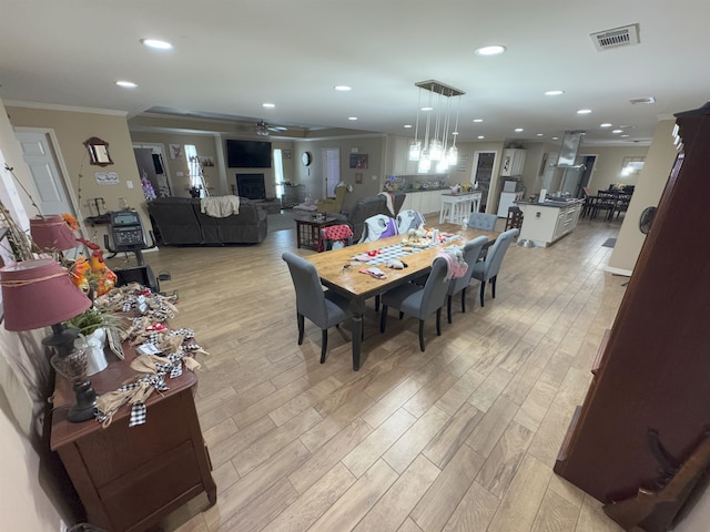 dining area featuring ornamental molding, ceiling fan, and light hardwood / wood-style flooring