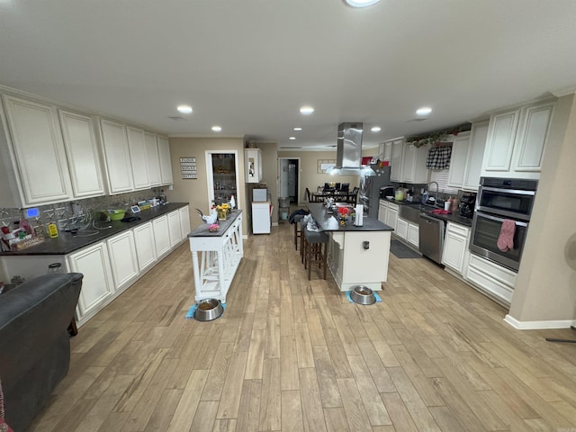 kitchen with a kitchen island, white cabinets, backsplash, and appliances with stainless steel finishes