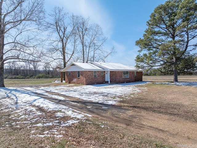 view of snow covered exterior with driveway and brick siding