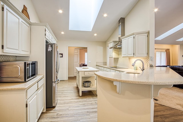 kitchen with stainless steel appliances, a breakfast bar, sink, white cabinetry, and kitchen peninsula