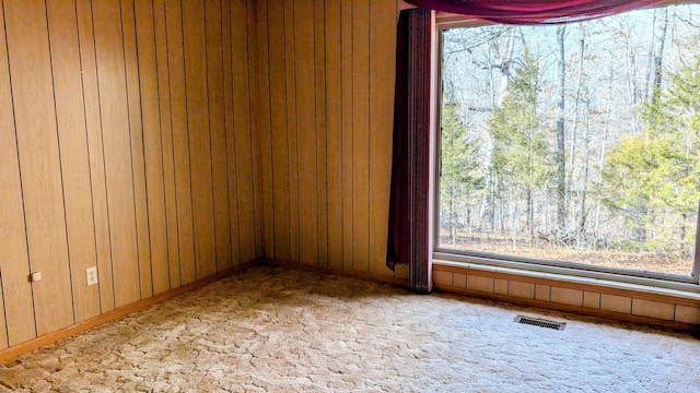 carpeted empty room with wooden walls