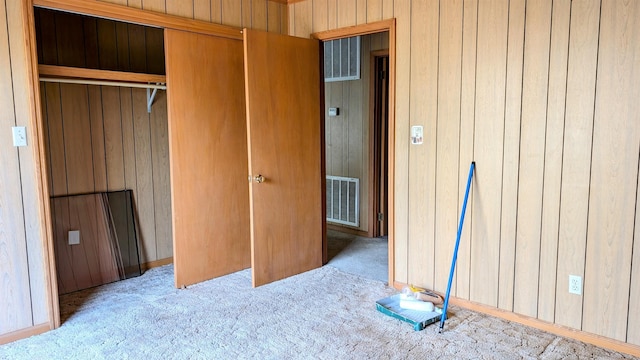 carpeted bedroom with a closet and wood walls