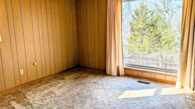 empty room featuring carpet flooring and wood walls