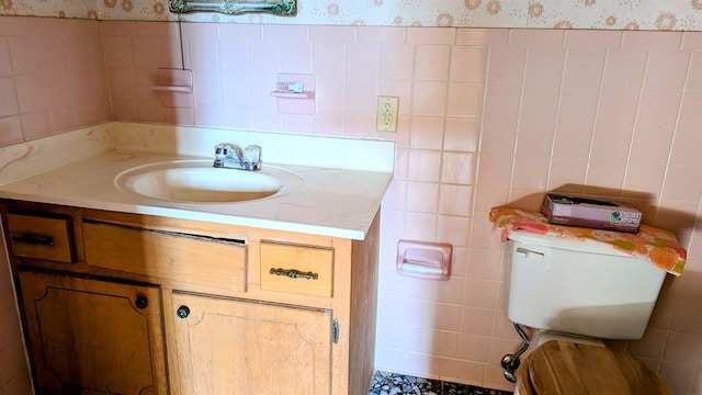 bathroom featuring vanity, tile walls, and toilet